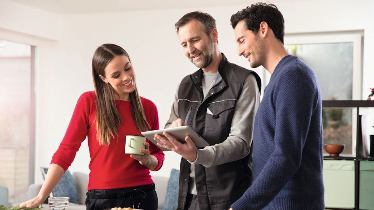 Un installateur Bosch conseille un client avec une tablette dans la cuisine